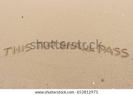 Handwriting  words "THIS TOO SHALL PASS" on sand of beach. Royalty-Free Stock Photo #653812975