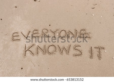 Handwriting  words "EVERYONE KNOWS IT" on sand of beach.