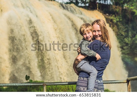 Mom and son on the background of Majestic landscape of Elephant waterfall in summer at Lam Dong Province, Dalat, Vietnam.
