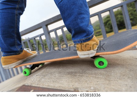 young skateboarder legs riding skateboard at skatepark ramp