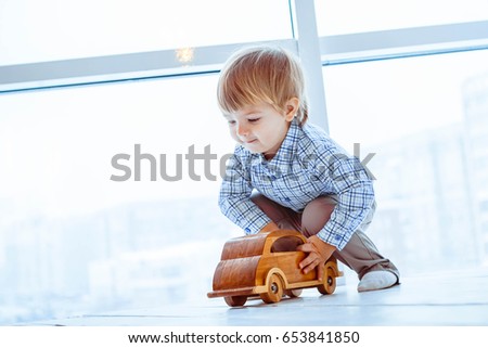 A boy is playing with toy cars near the window