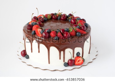 Birthday cake in chocolate with strawberries, blueberries and cherry on white background. Picture for a menu or a confectionery catalog.