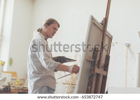 Creative male artist drawing picture oil paints