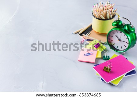 Back to school, children education concept. Assortment of supplies, crayons, pens, chalks, alarm clock. Copy space background