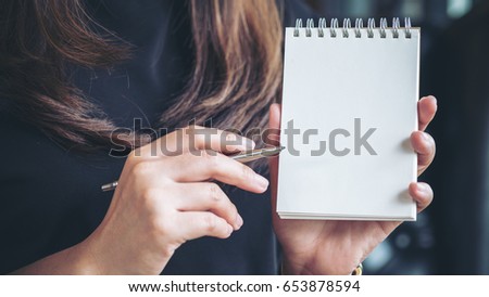 Closeup image of a woman holding and showing blank notebook in office