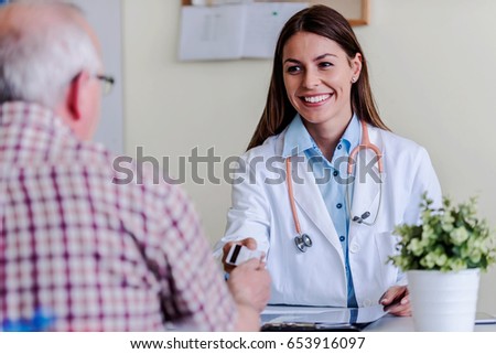 Older patient at woman doctor office paying exam with credit card Royalty-Free Stock Photo #653916097