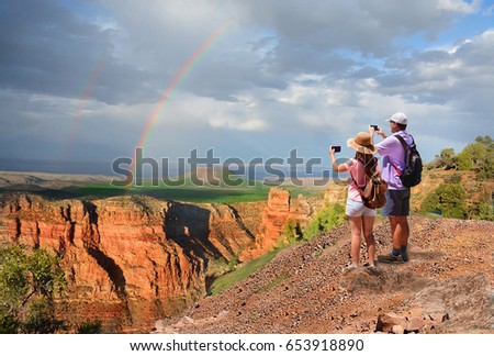 Family hiking on vacation,father and daughter  taking pictures with phone and relaxing on top of the mountain, looking at beautiful rainbow at sunset ,Grand Canyon National Park, Arizona, USA.