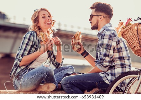 Happy young couple.They are laughing and eating sandwich and having a great time.