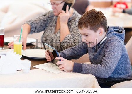 Smiled grandmother with a grand child using a tablet while eating. Cartoons and games at mealtime problem