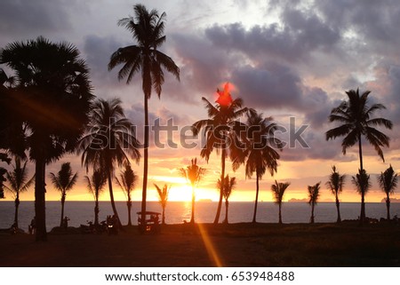 Travel to island Koh Lanta, Thailand. Palms tree on the background of the colorful sunset and cloudy sky.
