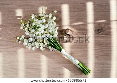 Wedding rings, bouquet of lily of the valley
