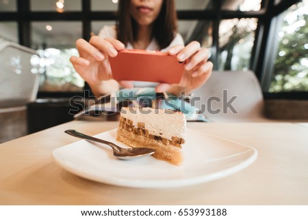 Hand of woman taking a photo of cake with smartphone.
