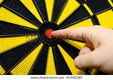 Male finger showing bulls eye on dart game board