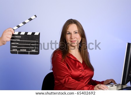 Woman with clapperboard in forground of image.