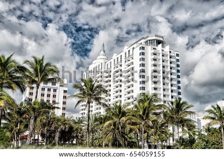 Miami. Modern architecture. High rise, apartment buildings or skyscrapers with green palm trees on foreground. City skyline with white clouds on sunny day on blue sky. Urban environment. Landmark