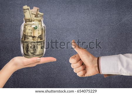 Female hand holding glass jar with money. Financial concept
