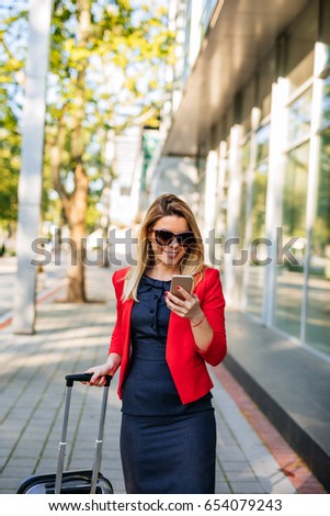 Beautiful woman texting on the phone while going on a business trip.