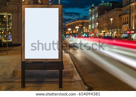 Vertical blank glowing billboard on night city street. In background buildings and road with cars. Mock up. Poster on street next to roadway. Space for logo, text, image, advertising, ad, blurb.