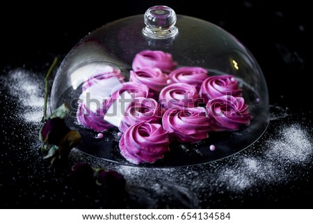 Many purple marshmallow on a dark surface. A contrasting picture. A work of culinary art.Under a glass cover