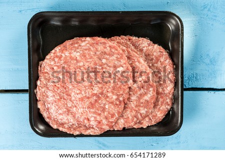 Raw minced meat burgers in the market package with price tag.