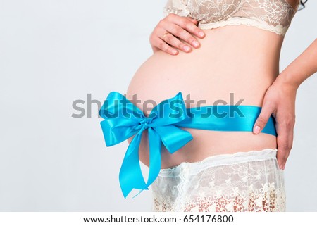 9 months. The tummy is tied with a blue ribbon. Pregnant girl waiting for the birth of her son.