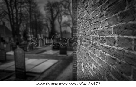 Dark old graveyard in black and white. Focus on the bricks of a church wall. Can be used as a spooky death background. 