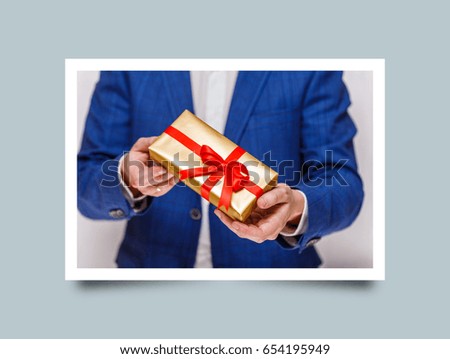 Male hands holding a gift box. Present wrapped with ribbon and bow. Christmas or birthday package. Man in suit and white shirt. Photo frame design with shadow.