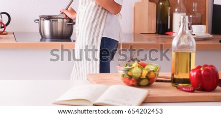 Portrait a smiling woman with phone in kitchen at home