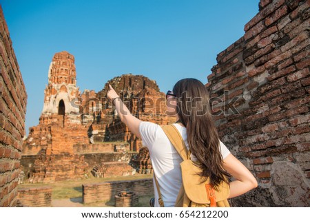 happy beautiful woman visiting Ayutthaya wat mahathat and pointing buddhist building sharing for family in Thailand travel with back view photo.