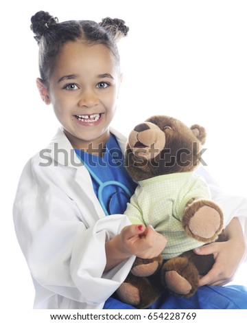 A happy elementary girl pretending to be a health care provider taking care of a patient's teddy bear.  On a white background.