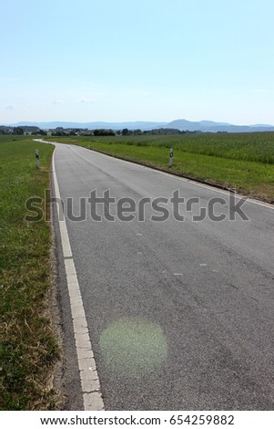 on a very sunny day in june in south germany you see summer landscape with green and blue sky and roads with signs to the horizon