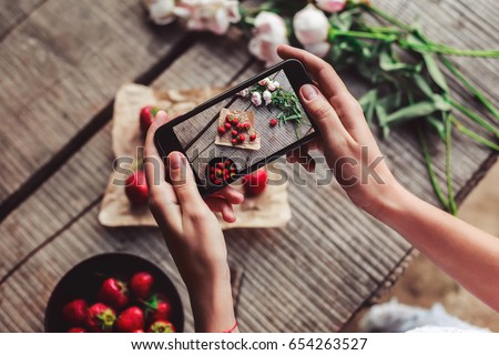 Girl's hands taking photo of breakfast with strawberries by smartphone. Healthy breakfast, Clean eating, vegan food concept. Top view