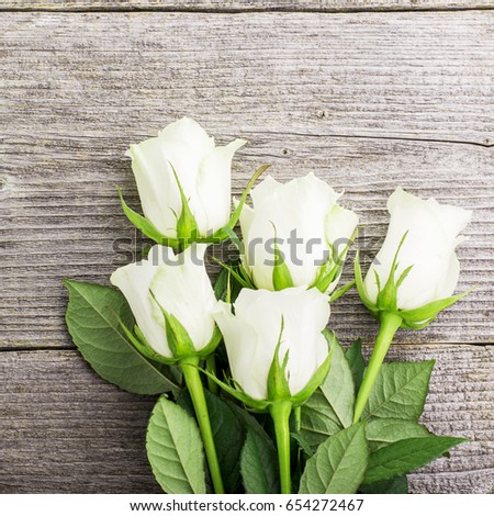A bouquet of white tea roses on a simple rustic gray wooden background. Top view. Romantic picture
