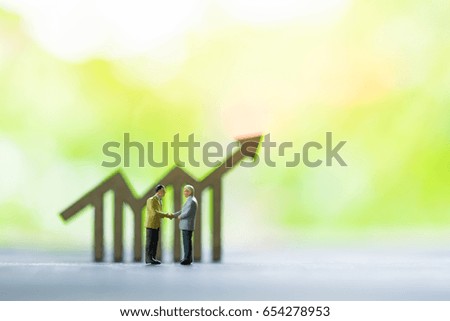 Miniature people: business man making decision on world map in front of wooden bar chart icon, success, dealing, greeting and partner concept.