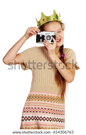 Little princess photographer holding camera and taking picture against white background