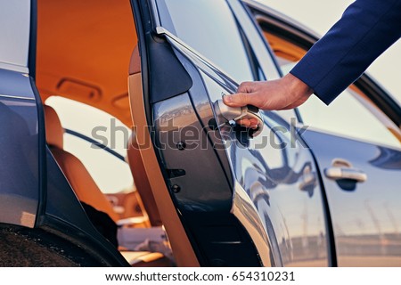 Close up image of a man opens car's door. Royalty-Free Stock Photo #654310231