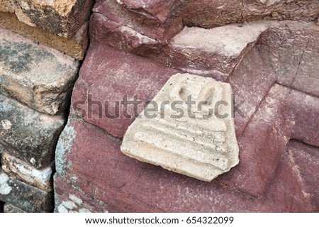 Abandoned broken Buddha image amulet left outside ruined sandstone pagoda in temple, northeastern Thailand