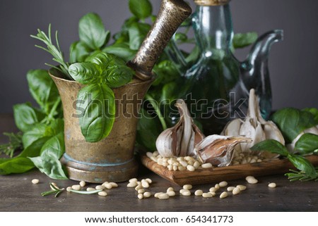 Ingredients for making pesto on a wooden table .Old copper mortar with olive oil, garlic, green basil and  pine nuts .