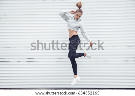 Fitness sporty girl in fashion sportswear dancing hip hop in the street, outdoor sports, urban style. Teen model in swag clothes posing outside. Royalty-Free Stock Photo #654352165