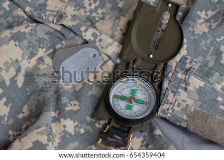 Army badge and compass on the background of camouflage.