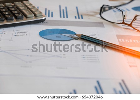charts and graphs with magnifying glass and pencil, calculator, clock. Reflection light and flare. Concept image of data gathering and statistical working.
