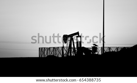 Silhouette of crude oil Bpu pump in oilfield at sunset.