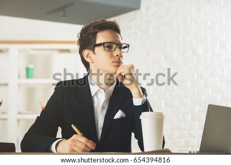 Portrait of handsome young gentleman doing paperwork at workplace