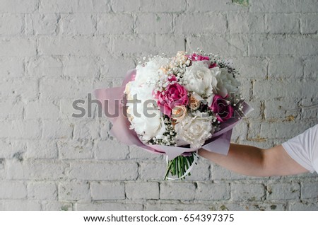 Bouquet of pink and white peonies in woman's hand with copy space rustic background.
