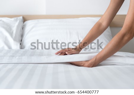 Hand set up white bed sheet in room Royalty-Free Stock Photo #654400777