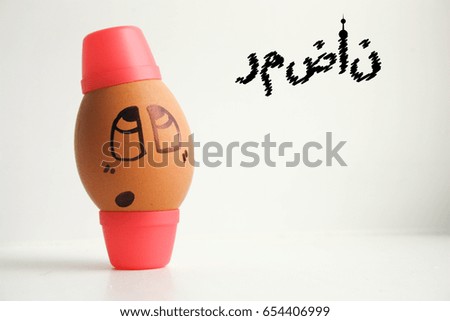 Egg with a cheerful painted face. Photo for your design. Ramadan. Egg in a hat with an inscription, in Arabic: Ramadan. 