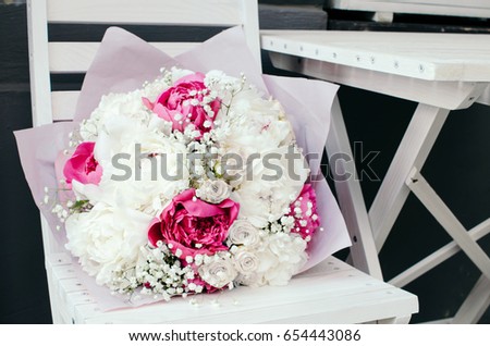 Bouquet of pink and white peonies on white chair 
