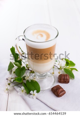 Glass full of delicious latte coffee with two chocolate candies