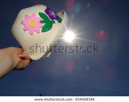 Hand holding baby straw hat int the sky (in the sun). Relax time, summer, holiday.