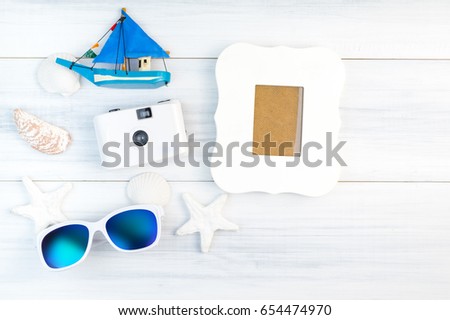 Beach accessories (White sunglasses,starfish,camera,boat,shell) and vintage white photo frame on white plaster wood table top view,Summer vacation concept.